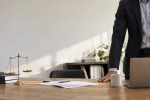 Un dirigeant en costume derrière un bureau avec une balance de la justice et des documents juridiques.